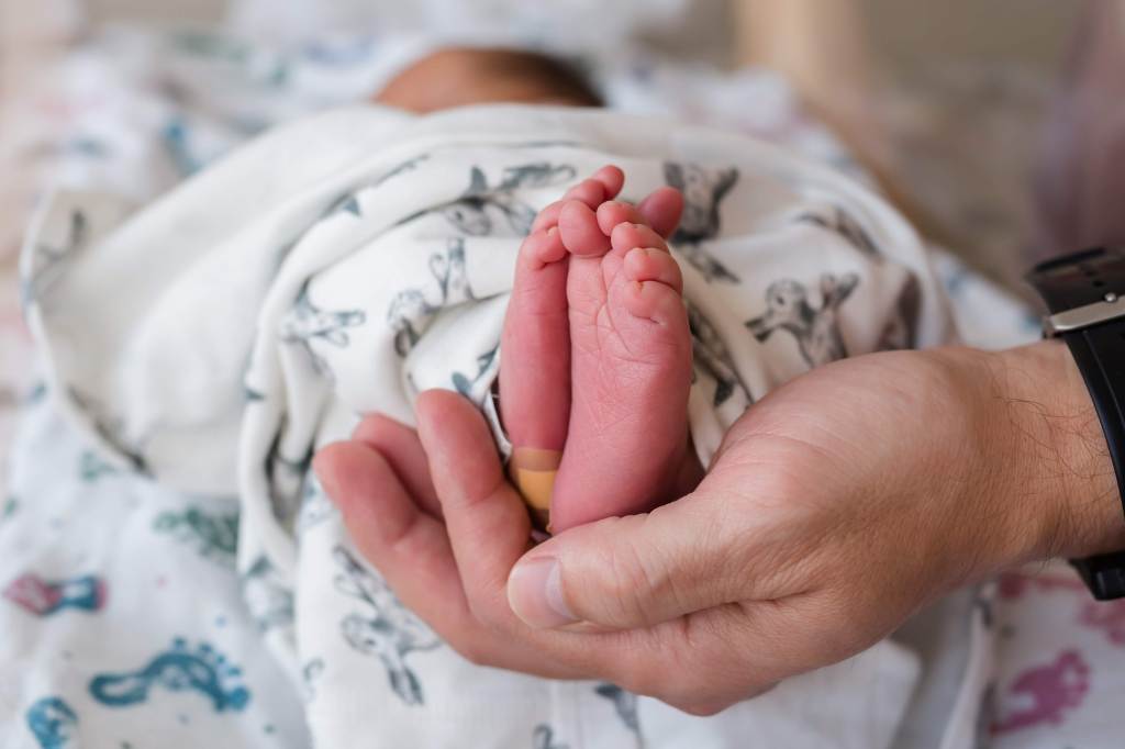 baby's feet held by father's hand